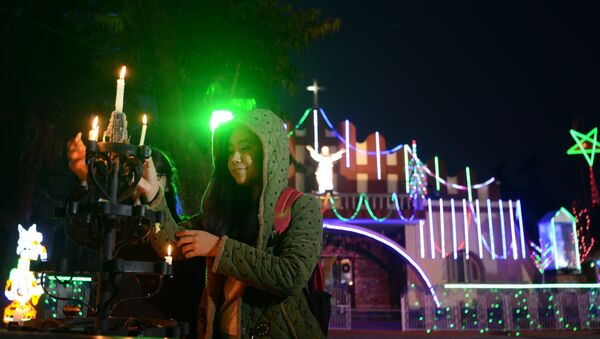 Indian Christians light candles near the illuminated Our Lady Queen Church on Christmas Eve in Siliguri - Sputnik International