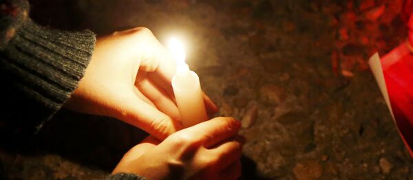 A woman places a candle to honour passengers and crew members of Russian military Tu-154 plane crashed into the Black Sea on its way to Syria on Sunday, at an embankmen in the resort city of Sochi, Russia December 25, 2016 - Sputnik International