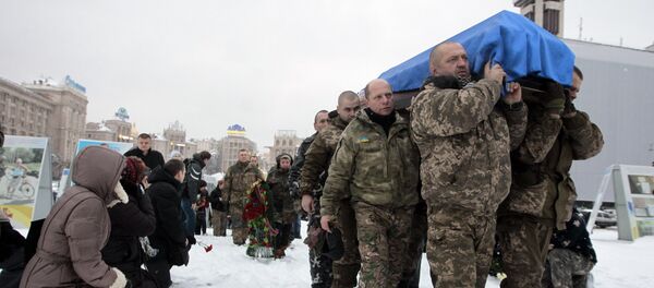 People, including servicemen and civilians, stand and kneel as the Ukrainian soldiers carry the coffin bearing the body of police captain Oleksandr Ilnitsky, who was shot dead by a sniper in the war conflict-hit Donetsk region, during a commemoration ceremony in Independence Square in Kiev, Ukraine, on Monday, Jan. 11, 2016 - Sputnik International