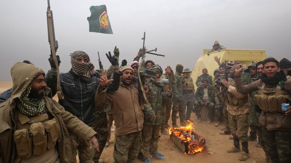 Iraqi Shiite fighters from the Hashed al-Shaabi (Popular Mobilisation) paramilitaries gesture to the camera as they warm up around a fire near the village of Tal Faris, south of Tal Afar, on November 30, 2016, during a broad offencive by Iraq forces to retake the city Mosul from jihadists of the Islamic State group - Sputnik International