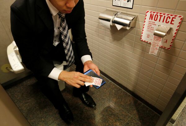A man demonstrates a toilet roll for wiping smartphones, installed by Japanese mobile phone company NTT Docomo at Narita international airport in Narita, Japan, December 28, 2016 - Sputnik International
