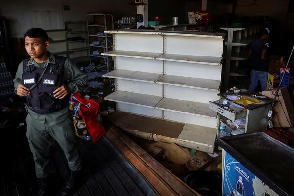 A Venezuelan National Guard stands guard as workers recover the valuables after a supermarket was looted in Ciudad Bolivar A Venezuelan National Guard stands guard as workers recover the valuables after a supermarket was looted in Ciudad Bolivar - Sputnik International