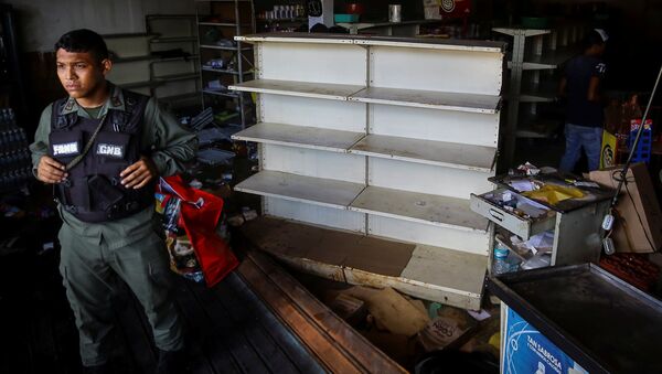 A Venezuelan National Guard stands guard as workers recover the valuables after a supermarket was looted in Ciudad Bolivar - Sputnik International