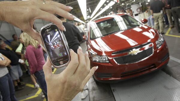 In this Sept. 8, 2010 file photo, auto worker Brenda Hedland takes a picture of the first Chevrolet Cruze compact sedan to come off the assembly line at a ceremony inside the GM factory in Lordstown, Ohio - Sputnik International
