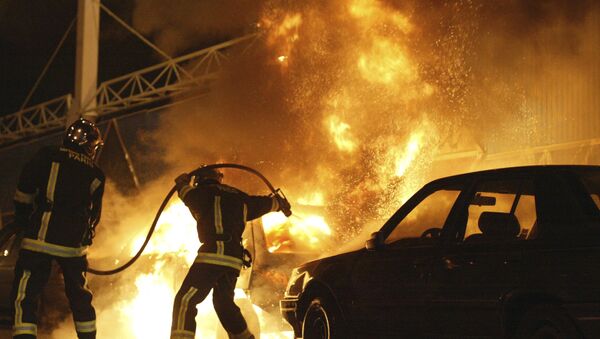 Firefighters work to extinguish a car set on fire during France's 2005 suburban riots - Sputnik International