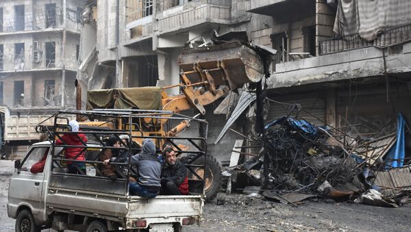 Syrian civilians drive past a tractor removing rubble as the Syrian government starts to clean up areas formerly held by opposition forces in the northern city of Aleppo on December 27, 2016, in the Shaar district. - Sputnik International