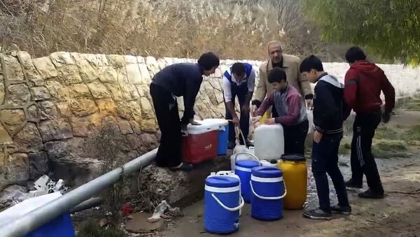 This frame grab from video provided By Yomyat Kzefeh Hawen Fi Dimashq (Diary of a Mortar Shell in Damascus), a Damascus-based media outlet that is consistent with independent AP reporting, shows Syrian residents filling up buckets and gallons of spring water from a pipe on the side of the road, in Damascus, Syria - Sputnik International