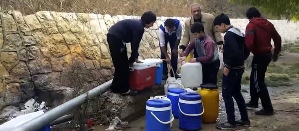 This frame grab from video provided By Yomyat Kzefeh Hawen Fi Dimashq (Diary of a Mortar Shell in Damascus), a Damascus-based media outlet that is consistent with independent AP reporting, shows Syrian residents filling up buckets and gallons of spring water from a pipe on the side of the road, in Damascus, Syria This frame grab from video provided By Yomyat Kzefeh Hawen Fi Dimashq (Diary of a Mortar Shell in Damascus), a Damascus-based media outlet that is consistent with independent AP reporting, shows Syrian residents filling up buckets and gallons of spring water from a pipe on the side of the road, in Damascus, Syria - Sputnik International