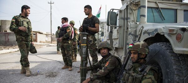 Iraqi Kurdish Peshmerga fighters rest next to their vehicles after returning from combat against Islamic State (IS) group jihadists in Bashiqa on November 9, 2016 - Sputnik International