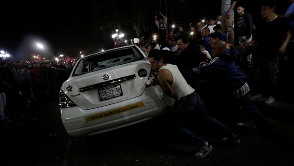 Demonstrators push over a vehicle of Multimedios TV network during a protest against the rising prices of gasoline enforced by the Mexican government at the Macroplaza in Monterrey, Mexico, January 5, 2017 - Sputnik International