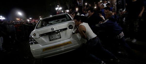 Demonstrators push over a vehicle of Multimedios TV network during a protest against the rising prices of gasoline enforced by the Mexican government at the Macroplaza in Monterrey, Mexico, January 5, 2017 - Sputnik International