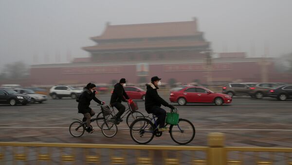 People wearing masks cycle past Tiananmen Gate during the smog after a red alert was issued for heavy air pollution in Beijing, China, December 20, 2016. - Sputnik International