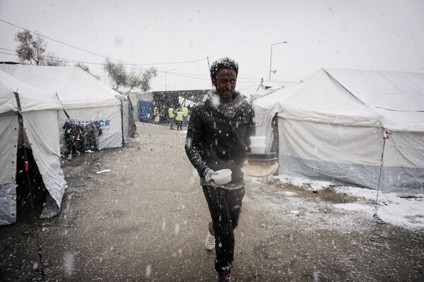 A migrant walks after receiving food during snowfall at the Moria hotspot on the Greek island of Lesbos, on January 9, 2017.  - Sputnik International