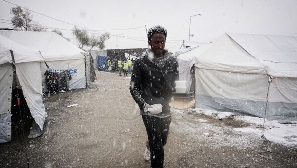 A migrant walks after receiving food during snowfall at the Moria hotspot on the Greek island of Lesbos, on January 9, 2017. - Sputnik International