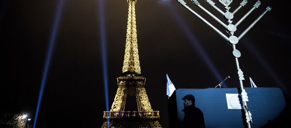 A member of the Jewish community stands near a Menorah (Hanukkah), a nine-branched candelabrum, before the lighting of two branches in front of the Eiffel tower in Paris on December 25, 2016. A member of the Jewish community stands near a Menorah (Hanukkah), a nine-branched candelabrum, before the lighting of two branches in front of the Eiffel tower in Paris on December 25, 2016. - Sputnik International