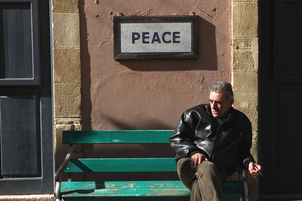 A man sits on a bench under a peace sign near the UN-controlled buffer zone in Nicosia, Cyprus January 9, 2017. A man sits on a bench under a peace sign near the UN-controlled buffer zone in Nicosia, Cyprus January 9, 2017. - Sputnik International