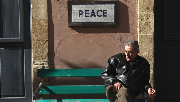 A man sits on a bench under a peace sign near the UN-controlled buffer zone in Nicosia, Cyprus January 9, 2017. - Sputnik International