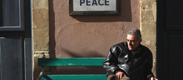 A man sits on a bench under a peace sign near the UN-controlled buffer zone in Nicosia, Cyprus January 9, 2017. - Sputnik International