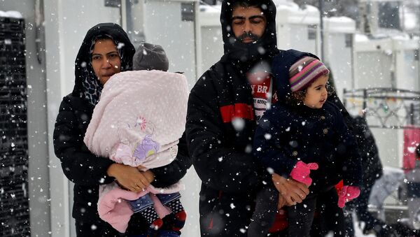 Stranded Syrian refugees carry their children through a snow storm at a refugee camp north of Athens, Greece January 10, 2017. - Sputnik International