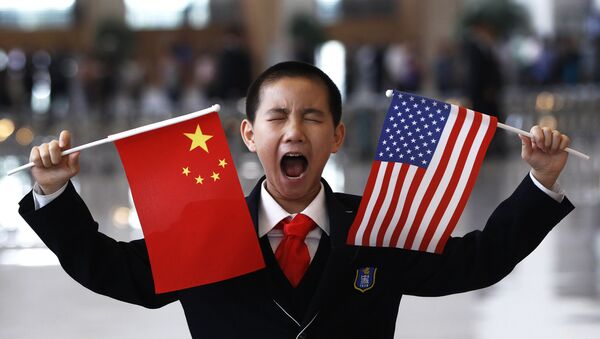 A little boy who is waiting to greet U.S. Secretary of State Hillary Rodham Clinton at the National Museum in Beijing makes a face while holding U.S. and Chinese flags Friday, May 4, 2012 - Sputnik International