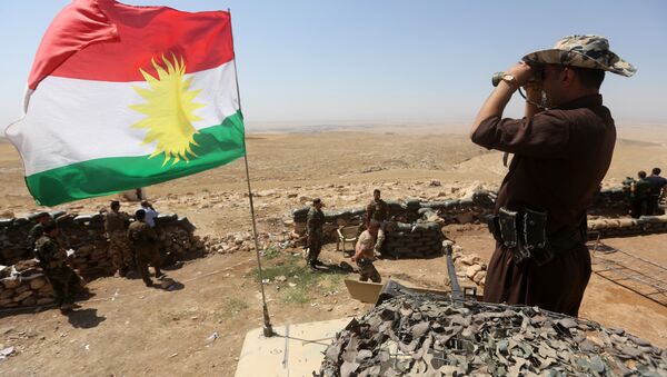 A flag of the autonomous Kurdistan region flies as Iraqi Kurdish Peshmerga fighters take position to monitor the area from their front line post in Bashiqa, a town 13 kilometres north-east of Mosul (File) - Sputnik International