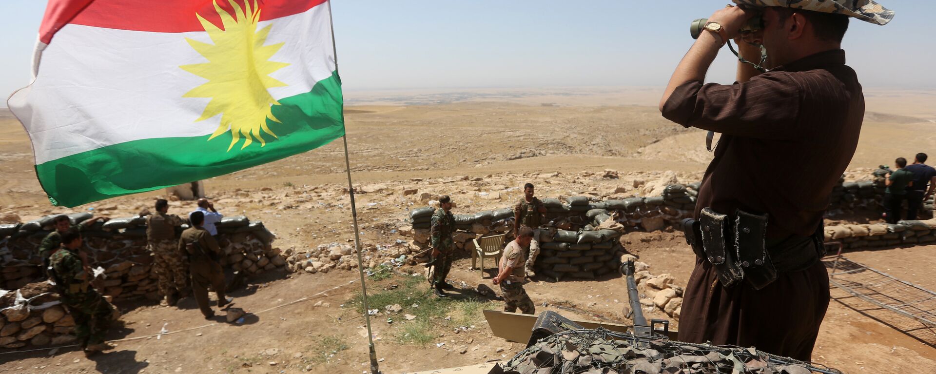 A flag of the autonomous Kurdistan region flies as Iraqi Kurdish Peshmerga fighters take position to monitor the area from their front line post in Bashiqa, a town 13 kilometres north-east of Mosul (File) - Sputnik International, 1920, 26.10.2023
