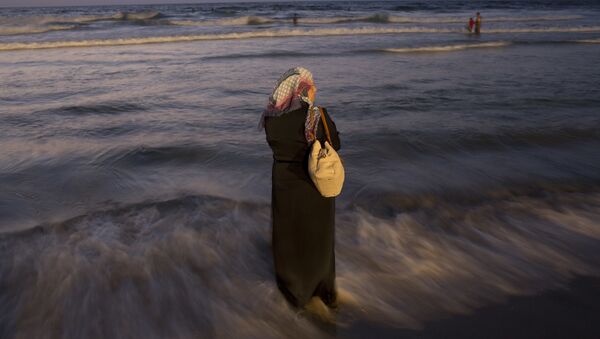 A Palestinian woman stands in the water on the beach during the Muslim Eid al-Adha holiday, in Tel Aviv, Israel, Wednesday, Sept. 14, 2016. - Sputnik International