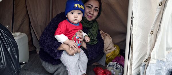An Afghani refugee woman and mother of three poses with one of her children in their tent set up on a baseball field at a refugee camp in the Hellinikon Olympic Complex, in a southern Athens suburb, on January 11, 2017. An Afghani refugee woman and mother of three poses with one of her children in their tent set up on a baseball field at a refugee camp in the Hellinikon Olympic Complex, in a southern Athens suburb, on January 11, 2017. - Sputnik International
