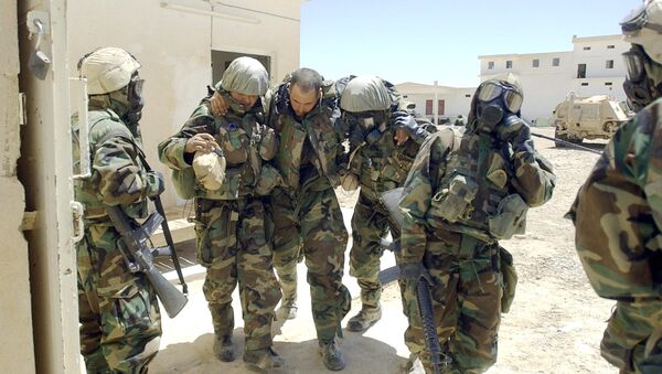 A US Army soldier from 2-8 Infantry, 2nd Brigade, 4th Infantry Division wearing his full chemical protection suit and suffering from heat exhaustion is helped by other soldiers after they sucured an industrial complex which they thought was a possible site for weapons of mass destruction in the central Iraqi town of Baquba 01 May 2003. - Sputnik International