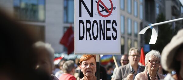 A woman holds a poster against drones during a demonstration against the upcoming visit of United States President Barack Obama in Berlin, Monday, June 17, 2013 - Sputnik International