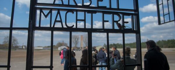 People are seen behind the gate reading Arbeit macht frei (work makes you free) at the entrance to the memorial site of the former Sachsenhausen Nazi concentration camp as they arrive to attend an event to commemorate the 70th anniversary of the camp's liberation, on April 19, 2015 in Oranienburg near Berlin, northeastern Germany. - Sputnik International