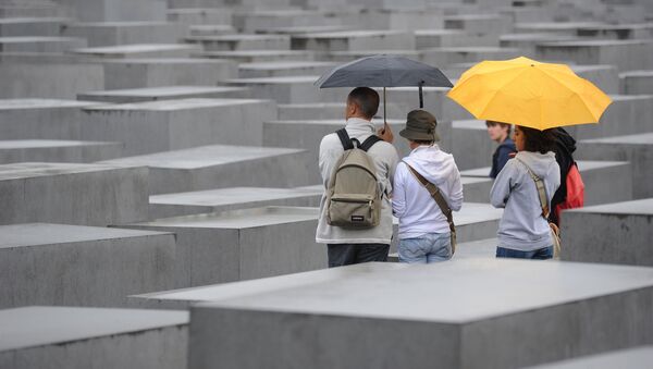 Tourists with umbrellas walk through the Holocaust Memorial on July 28, 2011 in Berlin. - Sputnik International