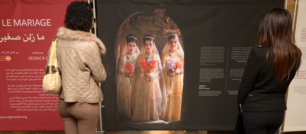 Moroccan women look at photographs of under-age brides during an exhibition by Stephanie Sinclair at the Mohammed V theatre in Rabat on December 4, 2013 - Sputnik International