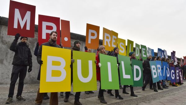 Activists from Greenpeace display a message reading Mr. President, walls divide. Build Bridges! along the Berlin wall in Berlin on January 20, 2017 to coincide with the inauguration of Donald Trump as the 45th president of the United States - Sputnik International