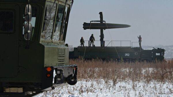 Russian soldiers watch a transporter-loader place an Iskander-M shorter-range missile onto a self-propelled launcher - Sputnik International