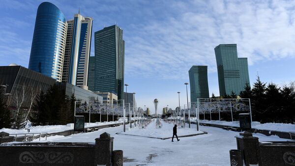 A picture taken on January 22, 2017 shows a man walking in downtown Astana, with the Baiterek monument seen in the background - Sputnik International