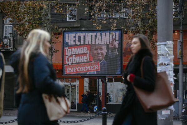 Pedestrians walk by a billboard picturing US President-elect Donald Trump with an inscrpition that translates as Congratulations! Trump, Serb! published by Serbian daily newspaper in Belgrade on November 10, 2016 - Sputnik International