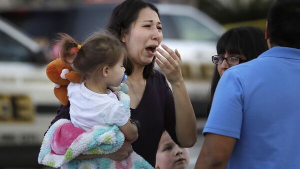 A woman holds her child after San Antonio police helped her and other shoppers exit the Rolling Oaks Mall, Sunday, Jan. 22, 2017, in San Antonio, after a deadly shooting. Authorities say several were injured after a robbery at the shopping mall. - Sputnik International