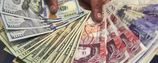 This file photo taken on October 04, 2016 shows a cashier displaying multiple denomination US dollar and British pound Sterling bank notes for a photograph inside a currency exchange store in central London on October 4, 2016. - Sputnik International
