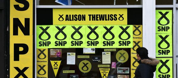 A member of the public walks past a window display of Scottish National Party branding is displayed in Glasgow, Scotland, Thursday, May 7, 2015 - Sputnik International