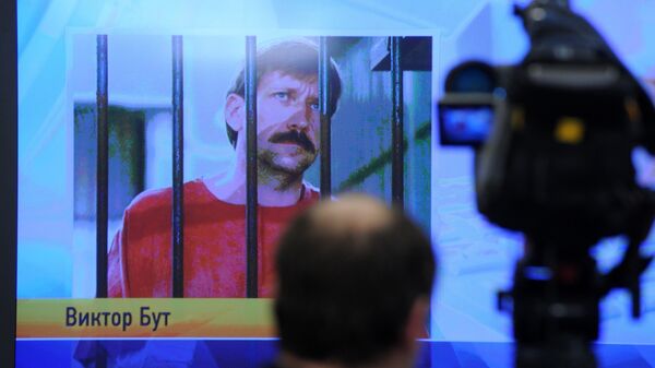 A journalist stands near a screen displaying convicted Russian arms smuggler Viktor Bout in Moscow, on April 12, 2012, during a teleconference with Bout from his US prison - Sputnik International