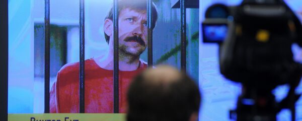 A journalist stands near a screen displaying convicted Russian arms smuggler Viktor Bout in Moscow, on April 12, 2012, during a teleconference with Bout from his US prison A journalist stands near a screen displaying convicted Russian arms smuggler Viktor Bout in Moscow, on April 12, 2012, during a teleconference with Bout from his US prison - Sputnik International