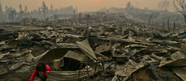 A young girl searches the wreckage of what was once her home in the fire-ravaged town of Santa Olga, Chile. A young girl searches the wreckage of what was once her home in the fire-ravaged town of Santa Olga, Chile. - Sputnik International