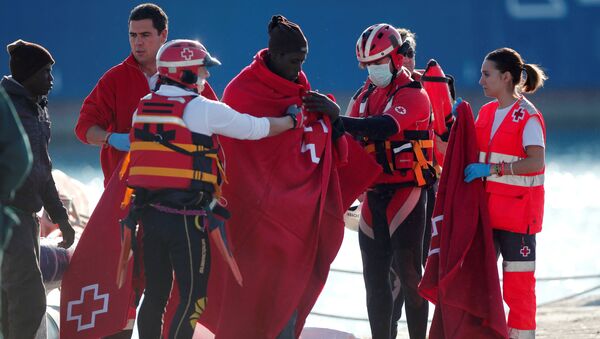 Migrants, who are part of a group intercepted aboard a dinghy off the coast in the Mediterranean sea, are assisted by members of Spanish Red Cross after arriving on a rescue boat at a port in Malaga, southern Spain, January 1, 2017 - Sputnik International