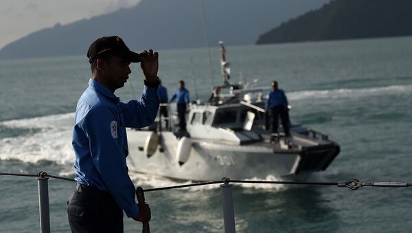 A Royal Malaysian Navy sailor (L) gestures as he stands aboard a naval ship during a search and rescue mission for boat-people, near the Thai-Malaysia border north of Langkawi island on May 28, 2015 - Sputnik International