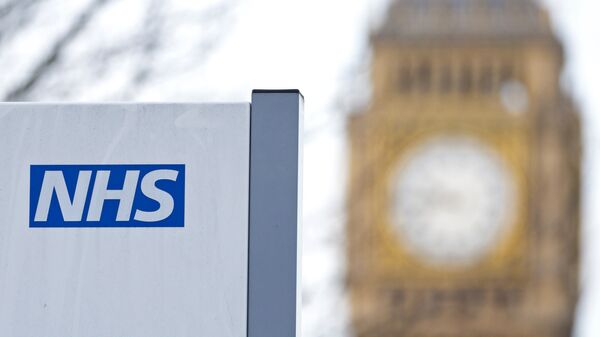 An NHS sign is pictured at St Thomas' Hospital in front of the Big Ben clock face and the Elizabeth Tower on January 13, 2017 in London.  - Sputnik International