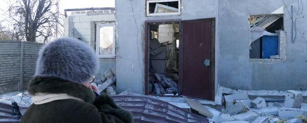 A woman by a house damaged by the shelling of the Ukrainian army in Donbass - Sputnik International
