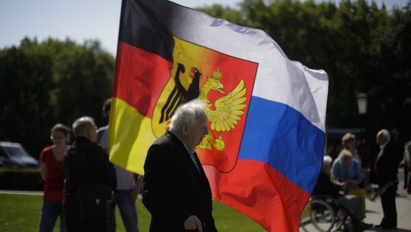 An old man stands in front of a combination of German and Russian national flags prior to a wreath laying ceremony at a Russian War Memorial to commemorate the end of World War II 71 years ago, at the district Tiergarten in Berlin, Germany, Monday, May 9, 2016 - Sputnik International
