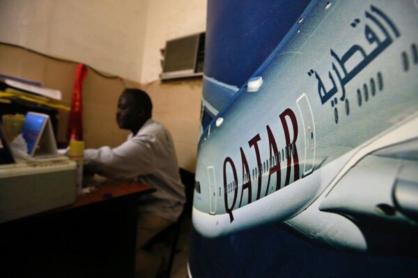 An image of a Qatar Airways plane is seen near an employee working at a travel agency in Khartoum, Sudan January 28, 2017 - Sputnik International