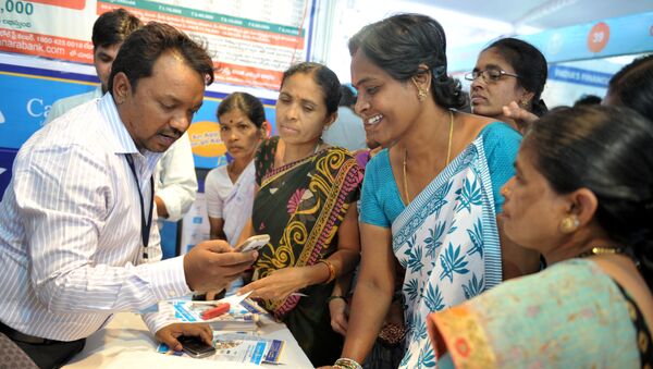 An Indian bank employee (L) explains to visitors about account transactions from a mobile phone with a Aadhaar or Unique Identification (UID) card during a Digi Dhan Mela, held to promote digital payment, in Hyderabad on January 18, 2017 - Sputnik International